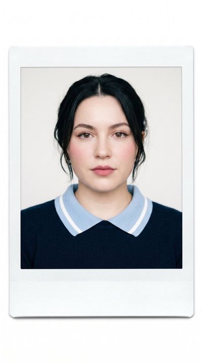 A young woman in navy sweater poses for minimalist portrait.