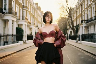 A seductive woman in a leather jacket poses on a London street