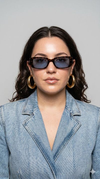 A confident model in retro sunglasses poses for editorial fashion portrait