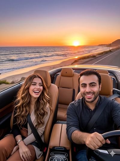Man drives Rolls-Royce convertible at sunset along coastal road