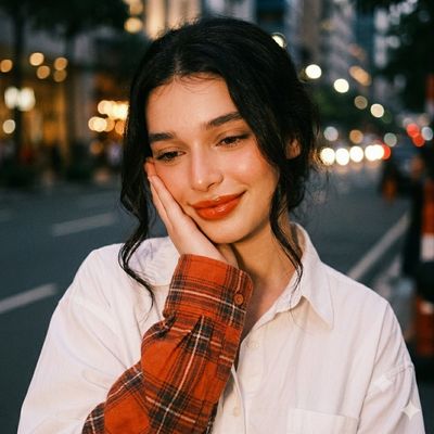 Woman in plaid sleeve shirt smiles softly against city lights