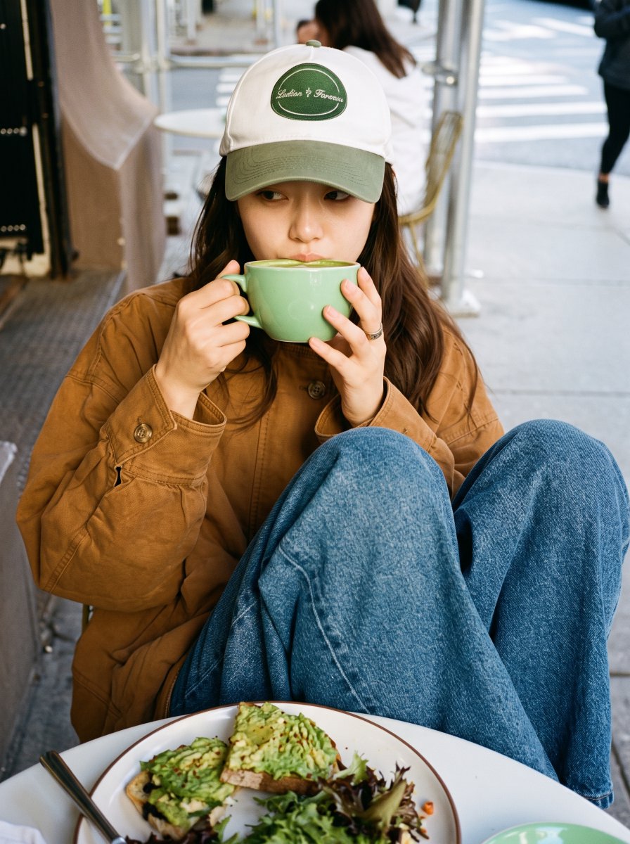 Woman in cap sips matcha at sunny city cafe