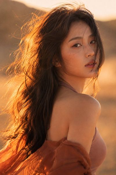 Warm wind catches a Korean woman's scarf in desert light