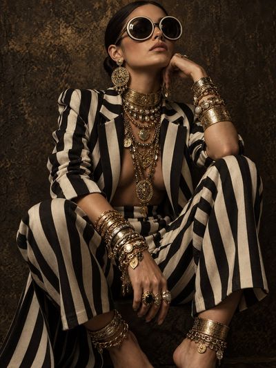 Gold jewelry avalanche swallows striped suit in dark editorial crouch