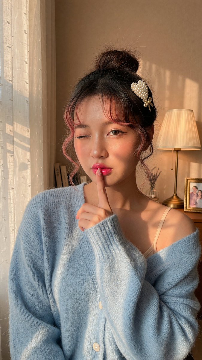 Young woman winks with finger to lips in cozy sunlight