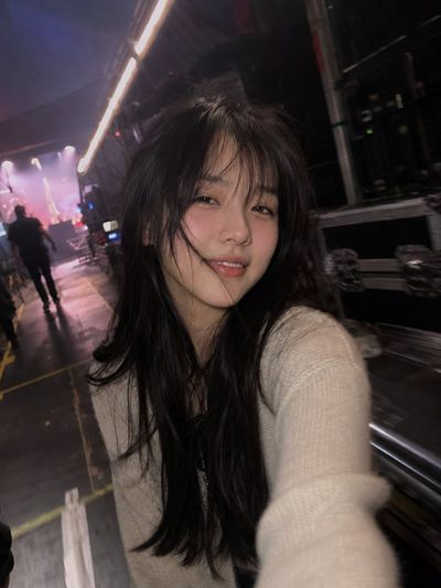 A woman with flushed cheeks smiles in a backstage corridor
