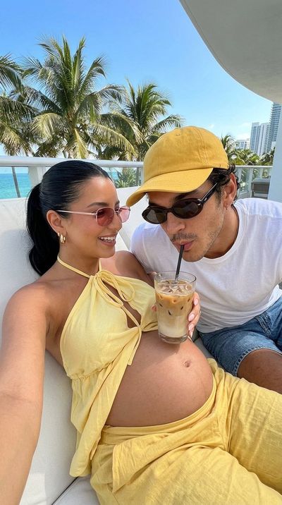 Pregnant woman relaxes with partner on sunny Miami balcony