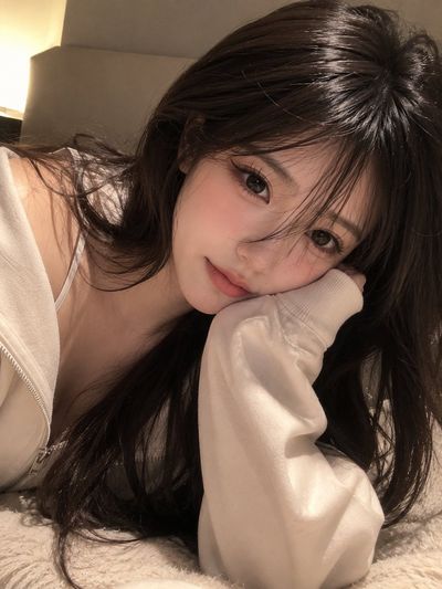 Young woman rests her cheek in a cozy cream hoodie sleeve