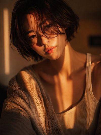 Woman with short bob hair catches golden hour shadows in a moody room