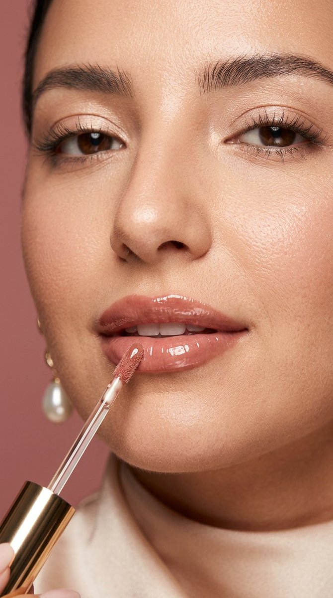 Luxurious rose-nude gloss applicator touches soft glossy lips