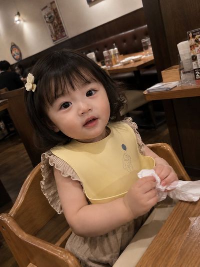 Toddler girl sits in high chair at cozy Japanese restaurant