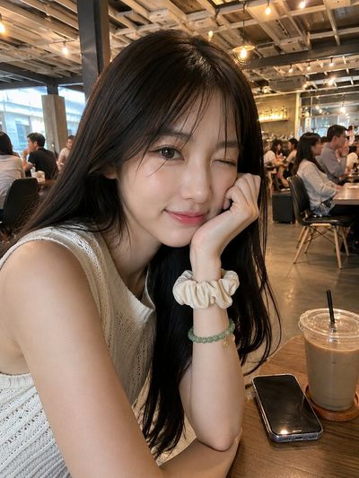 Young woman smiles gently in cozy café with warm lighting.