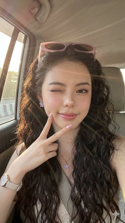 Young woman winks in a sunlit car during golden hour ride