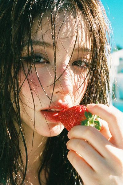 Sunlit Woman Holds Ripe Strawberry Near Glossy Lips in Summer Portrait