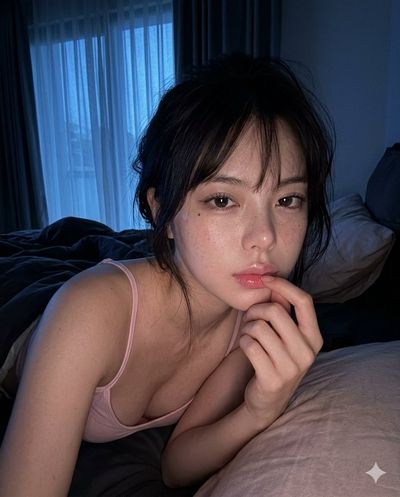 Woman rests in blue bedroom light with hand touching her lip