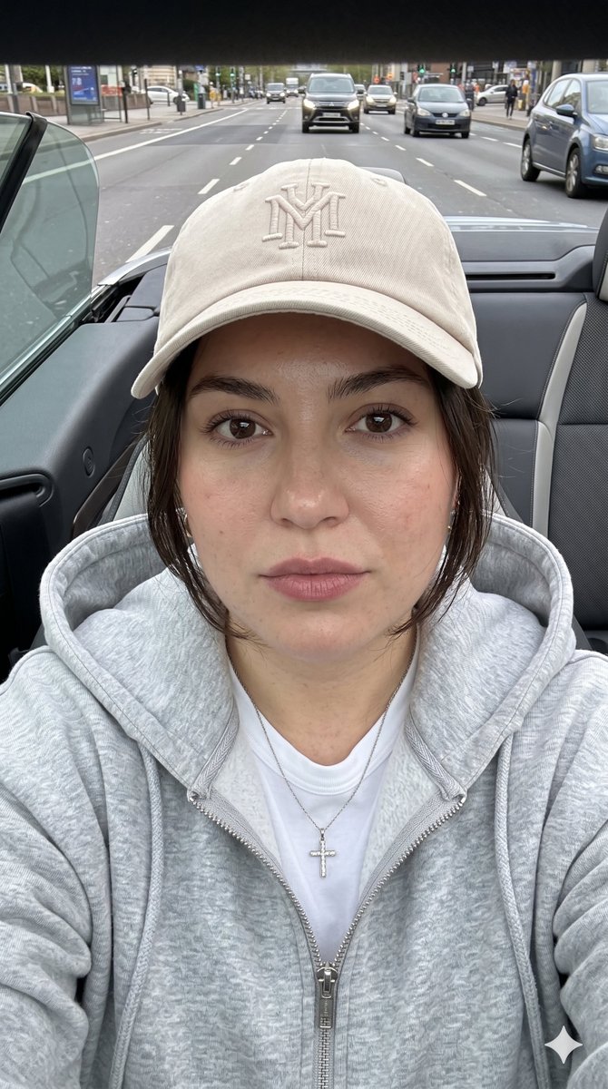 Model in beige cap and gray hoodie gazes calmly at camera