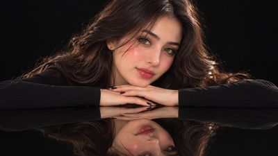 Black-clad muse with glossy reflection poses under studio lights