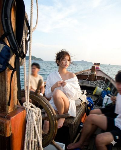 A woman rides a weathered boat while lost in afternoon thoughts.