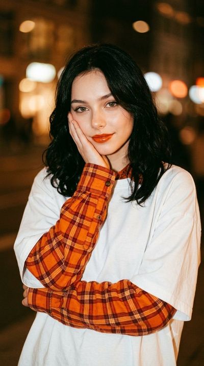 Young woman with wavy black hair smiles softly in warm amber glow
