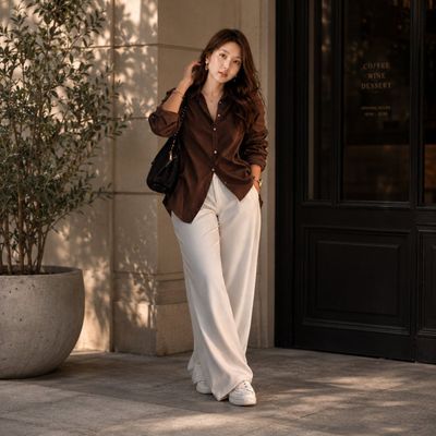 A stylish woman poses outside a luxury café at golden hour