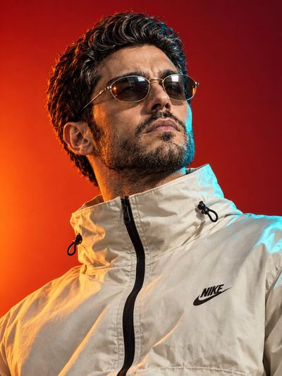 Confident man in vintage glasses poses against vibrant red background