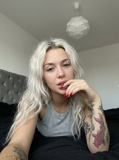 Intimate Snapshot of a Tattooed Woman in a Casual Bedroom Setting
