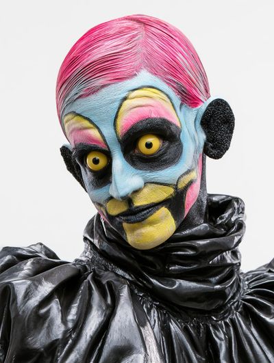 A model with pink hair and yellow eyes smiles in latex