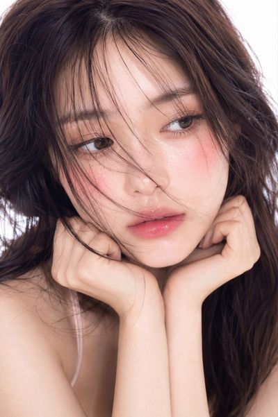 Young Korean woman with dewy glass skin poses in bright studio light