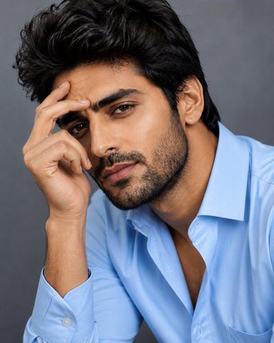 A sharp-featured man in a blue shirt gazes confidently at the camera.