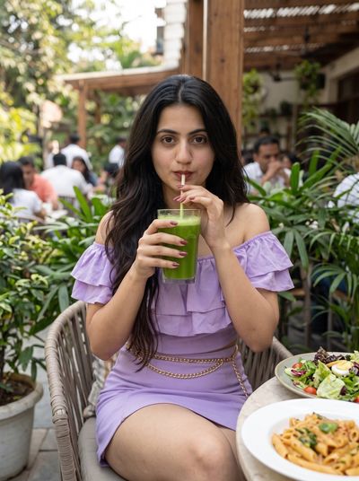 Young Woman Sips Green Juice at Outdoor Cafe Table