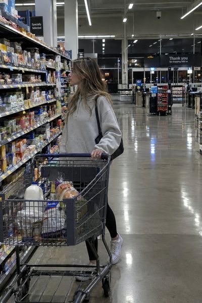 Young woman shops alone in empty supermarket under fluorescent lights