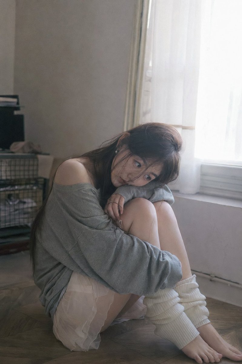 A melancholic Chinese girl rests by a sunlit window
