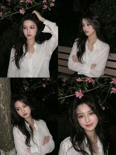A young Asian woman stands beneath pink blossoms at night