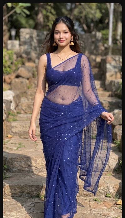 Young woman in blue sequined saree poses on stone steps