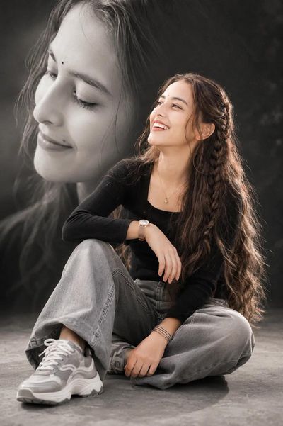 A laughing woman with braided hair sits in monochrome art