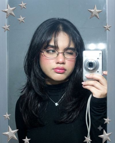 A Y2K mirror selfie captures long dark hair and flash
