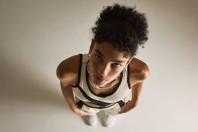 A model in sleek reflective fashion poses under soft studio light