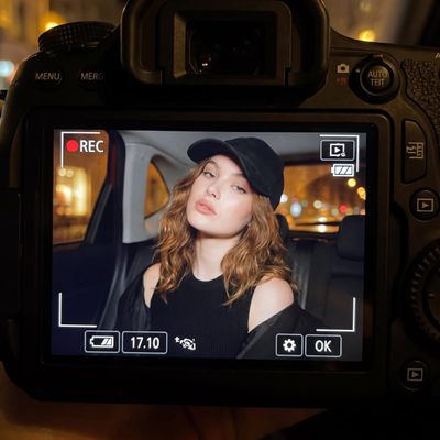 A young woman poses casually in a car at night with a mysterious expression