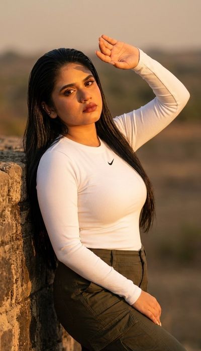 A woman shields her eyes from the setting sun's warm golden light.