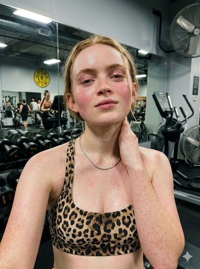 Glistening athlete pauses after intense workout in gym mirror