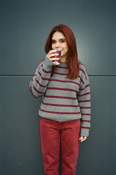 Cinematic close-up of girl drinking iced latte against grey wall