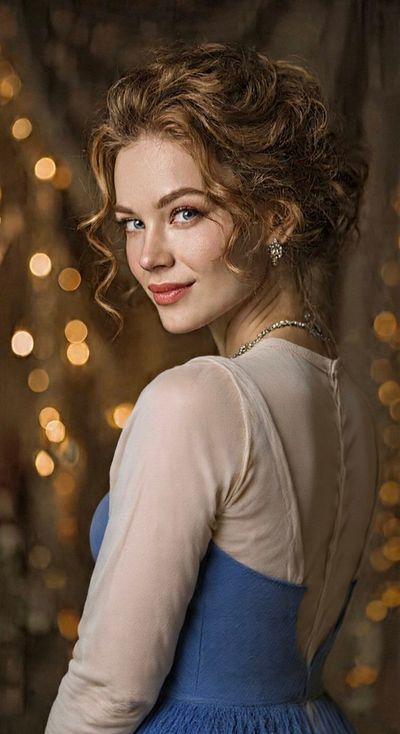 A woman with blue eyes turns gracefully in warm golden light