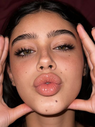 A woman with closed eyes makes a kissy face in a car