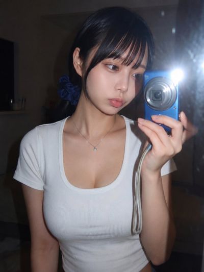 Young woman captures a mirror selfie with bright camera flash