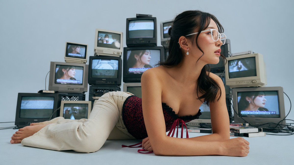 Japanese model lies among vintage monitors in burgundy corset