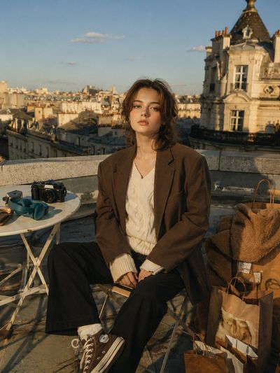 A young girl sits on a rooftop chair during golden hour