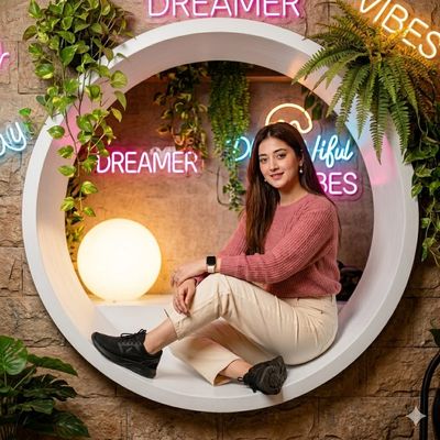 Young woman sits in a wooden nook with neon lights and plants.