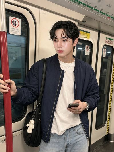 Young man with a smartphone stands casually in a subway train