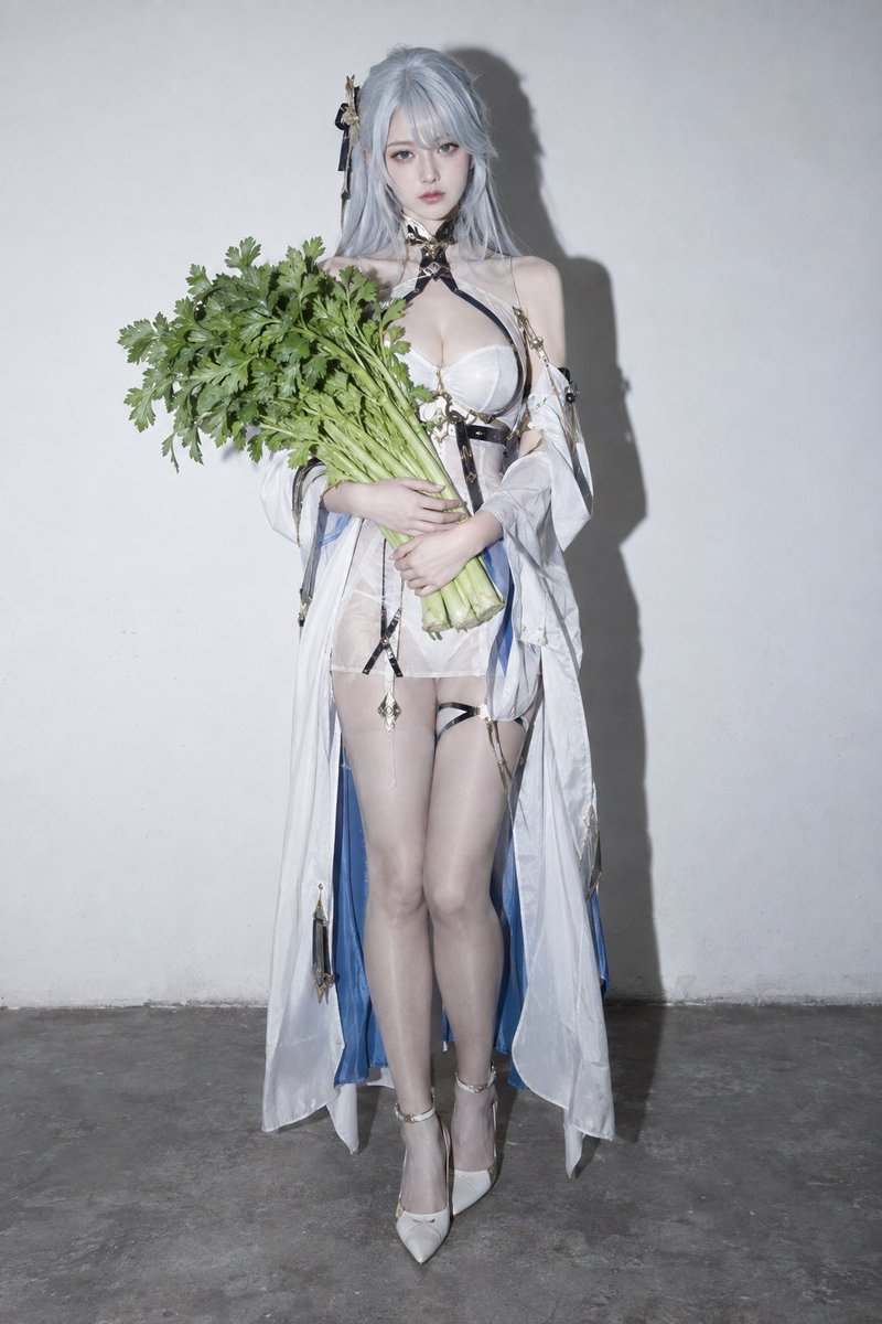 Cold adult cosplayer clutches fresh celery against stark white wall
