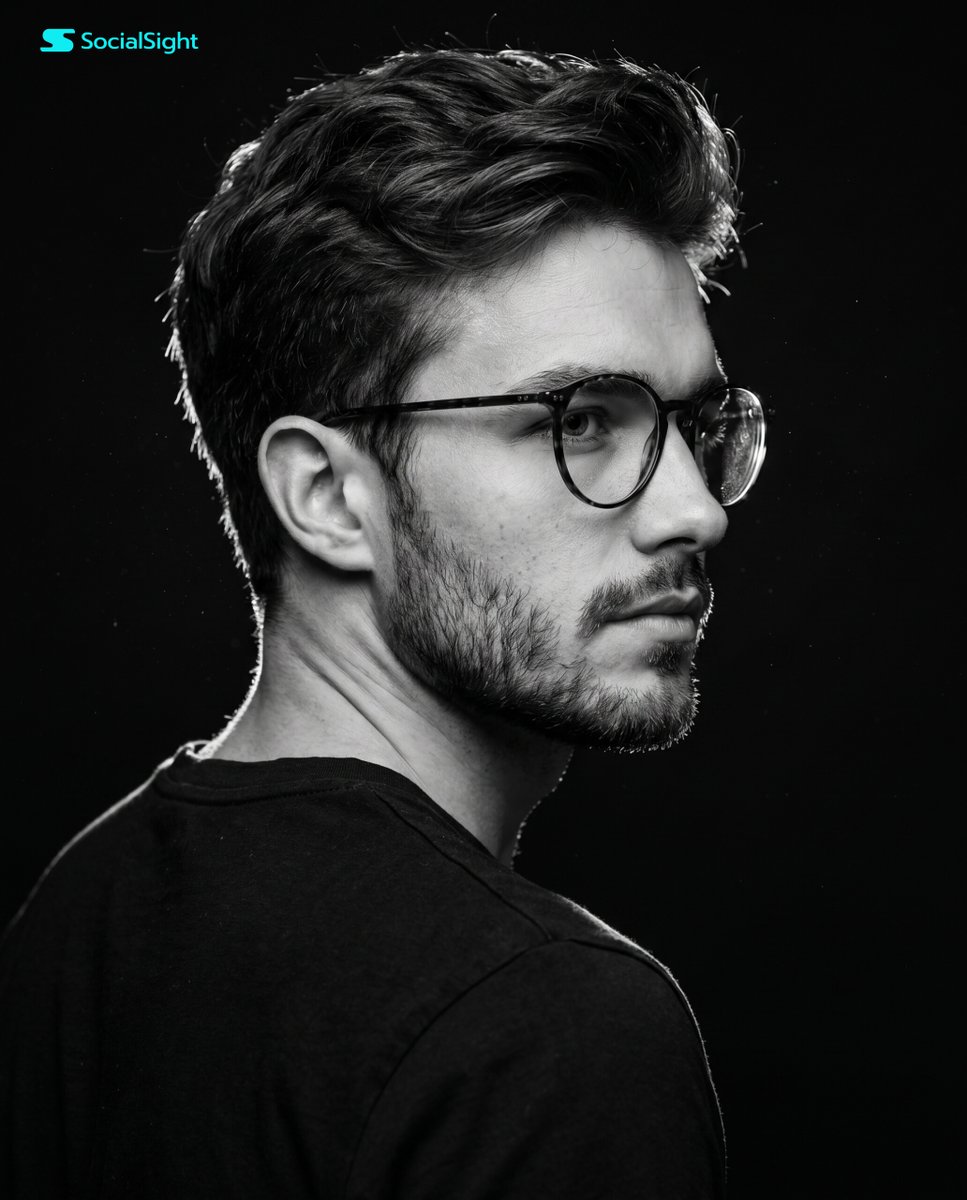 A young man with dark hair turns in a dramatic side profile